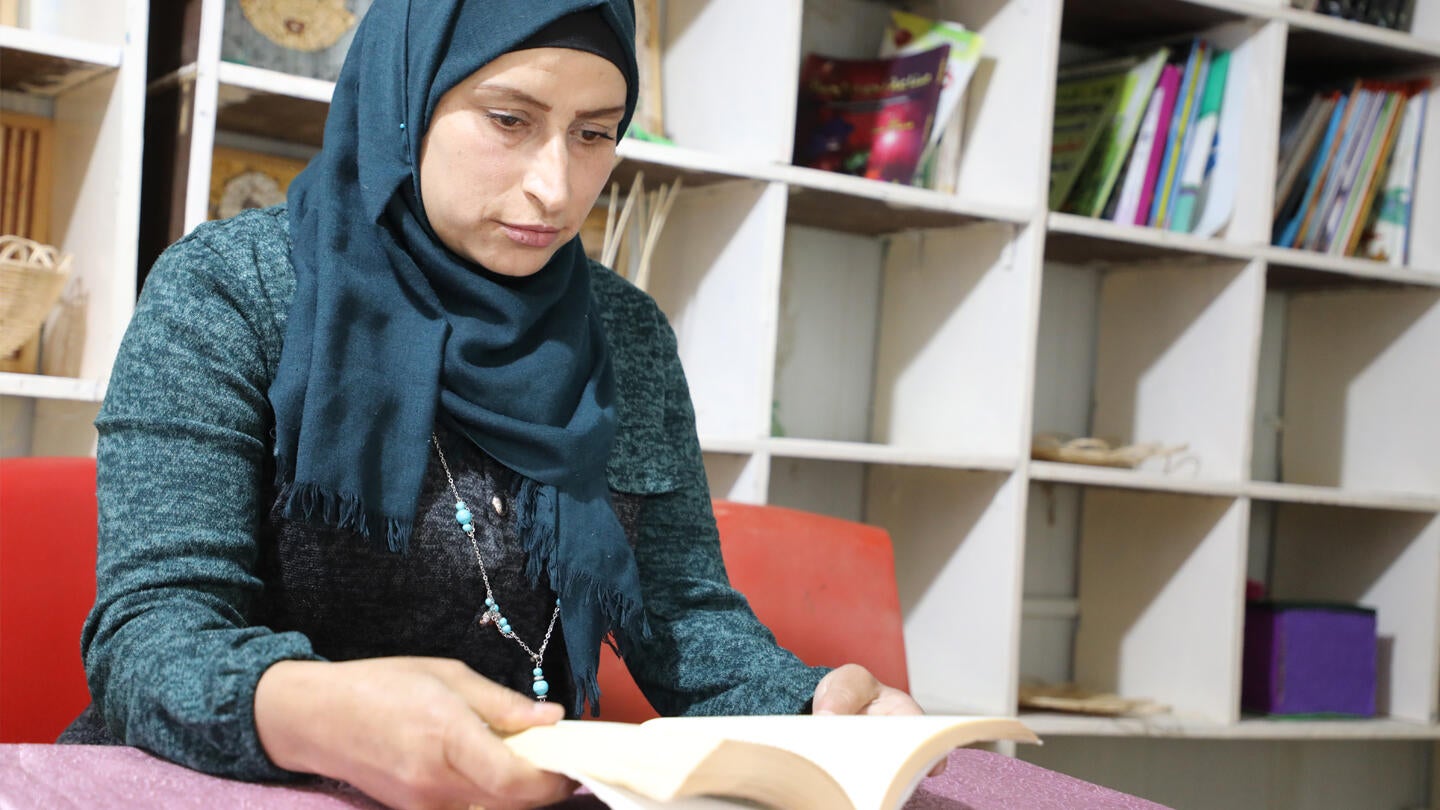 Rabia enjoys reading a book at the library in the Women and Girls Safe Space.